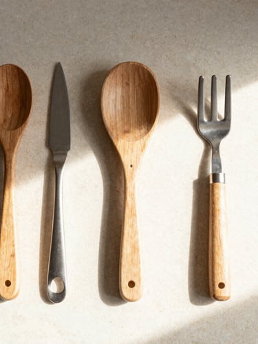 Overhead flat lay of beautifully organized wooden and steel kitchen tools on a light stone counter, soft natural morning sunlight, warm shadows, 35mm editorial photography