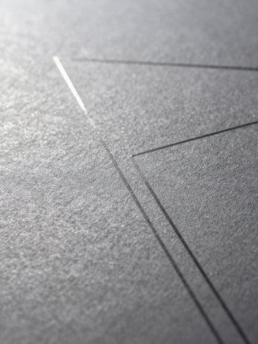 Macro close-up of fine-textured heavy cotton paper with a subtle debossed geometric line, dramatic side-lighting, silver and charcoal tones, sharp focus.