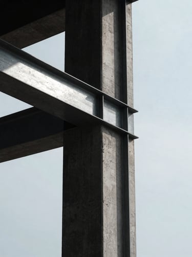 Portrait-oriented architectural detail of a concrete column meeting structural steel, cool overcast natural light, sharp side shadows, deep charcoal and silver tones, high-contrast, minimalist, 35mm.