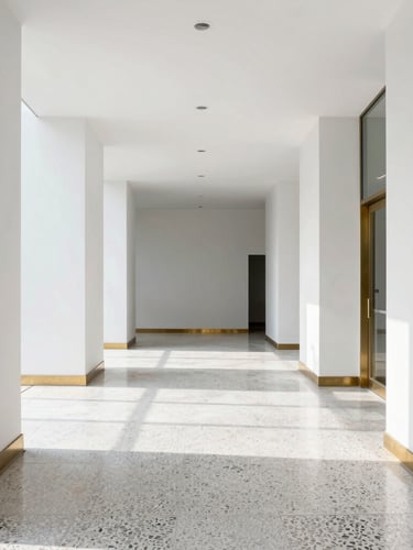 Straight-on architectural photograph of a minimalist corporate lobby with polished terrazzo flooring and raw brass trim, bright natural daylight, crisp slate tones, sharp focus