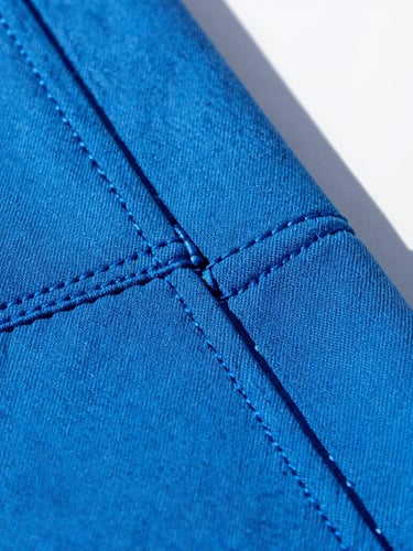 Close-up macro shot of durable double-stitched seams on vibrant electric blue canvas fabric, bright natural sunlight, crisp shadows, 35mm