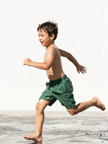 Energetic young boy running through sprinklers in a sunny backyard, wearing durable green shorts, dynamic action shot