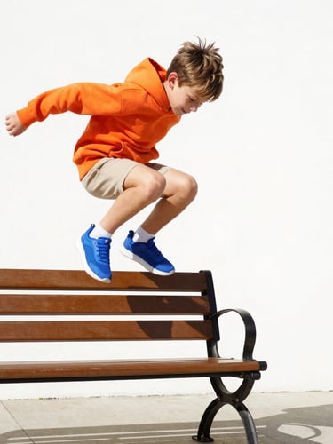 Low-angle dynamic action shot of a young boy jumping off a park bench in bright, high-key natural sunlight, wearing a vibrant orange hoodie and electric blue sneakers, clean white background, energetic shadows, 35mm