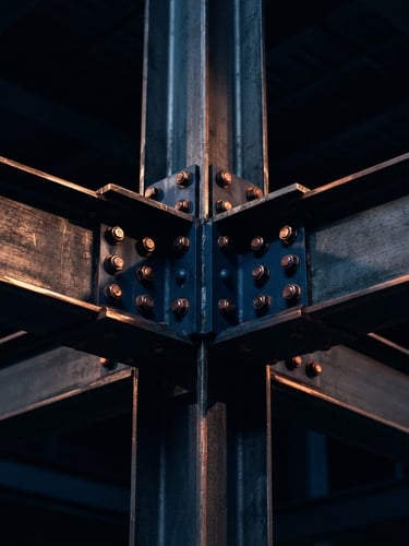 Macro photograph of high-end structural steel beams reflecting dramatic low-key copper light, deep midnight sapphire shadows, sharp focus, architectural symmetry, 35mm