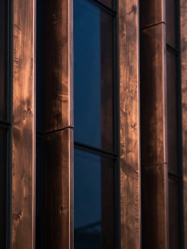 Extreme macro detail of brushed copper and dark glass architectural panels, dramatic low-key lighting with deep sapphire shadows, sharp focus, 35mm