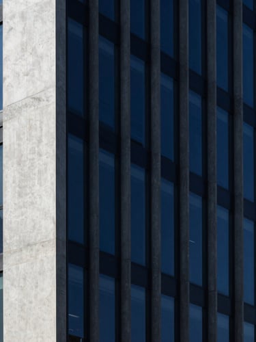 Minimalist modern concrete and glass skyscraper facade, sharp high-contrast studio light, deep indigo shadows, 35mm lens