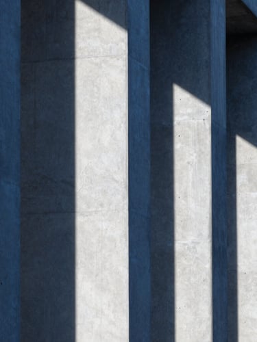 Close-up of brutalist architectural concrete columns, sharp geometric shadows, cool blue and white tones, architectural crop
