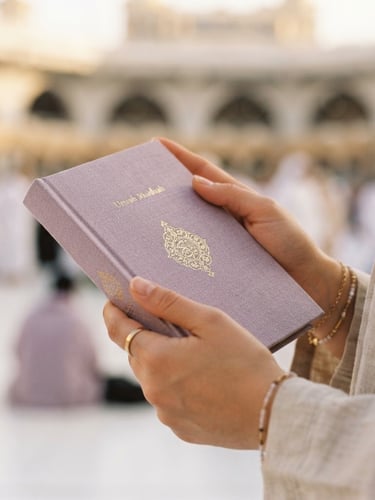 Close-up of hands holding a linen-bound Umrah guidebook in soft morning light, shallow depth of field, 35mm