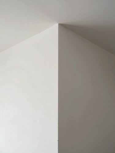 Straight-on geometric perspective of a perfectly finished drywall corner, crisp white paint, natural daylight casting clean shadows, architectural precision.