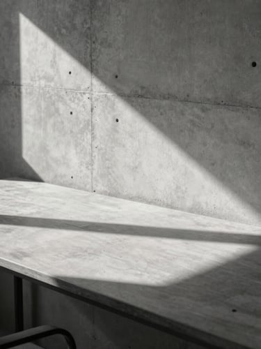 A sharp architectural crop of a minimalist concrete creative studio with hard sunlight casting long shadows across a clean work desk.