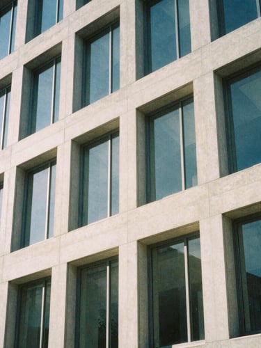 An architectural close-up of a modern concrete and glass building facade in Salt Lake City, soft morning daylight, cool shadows, minimalist composition.