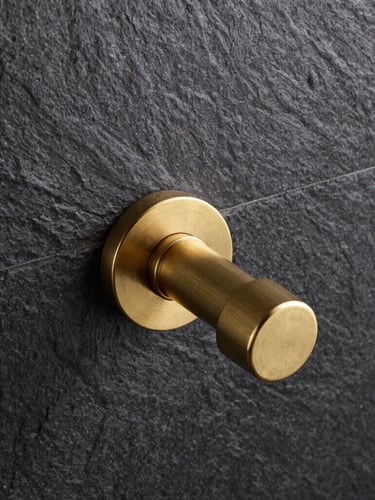Straight-on architectural elevation of a minimalist brass shower valve installed perfectly flush against dark textured slate tiles, sharp industrial photography, 50mm