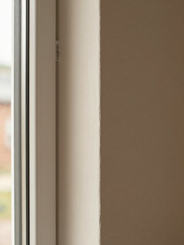 The same interior wall after remodel—smooth painted finish, new window casing with clean mitered corners, warm natural daylight, documentary close-up showing edge quality