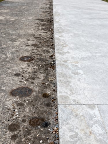 Extreme close-up split-screen before and after of a concrete driveway being restored from dark mold to bright clean stone