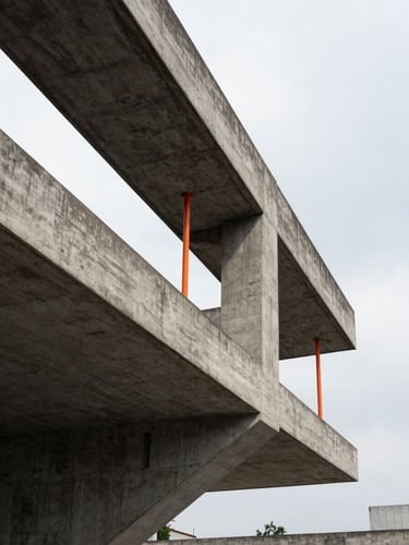 Low-angle architectural photography of a raw concrete cantilever structure in Mexico City, high-contrast overcast daylight, sharp shadows, safety orange accents