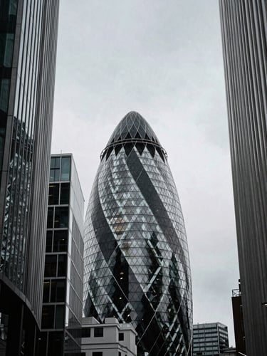 Low-angle high-contrast architectural crop of London's tech corridor buildings against a cool overcast sky, sharp shadows, desaturated tones, 35mm grain