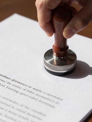Close-up of a corporate seal being applied to a clean, crisp legal document, bright natural daylight, sharp professional shadows