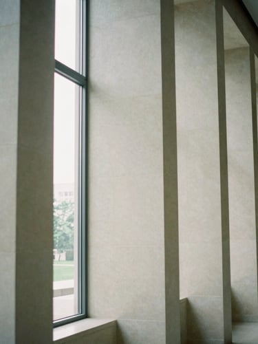 Abstract architectural geometry of a quiet stone library interior, clean vertical columns, soft diffused daylight, elegant minimalist atmosphere, 35mm film.