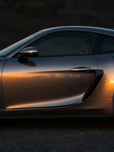 Moody dramatic side profile of a dark metallic sports car, golden hour reflections on the sleek paint, high contrast, professional automotive photography