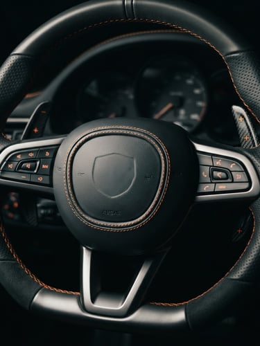 Close-up of a metallic grey sports car steering wheel, orange stitching details, low-key dramatic studio lighting, high contrast, 50mm lens
