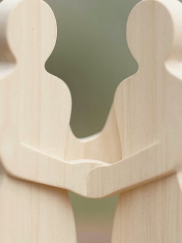 Close-up of abstract, hand-carved wooden figure with soft, organic lines, representing human connection, in warm ivory tones, soft natural daylight, shallow depth of field.