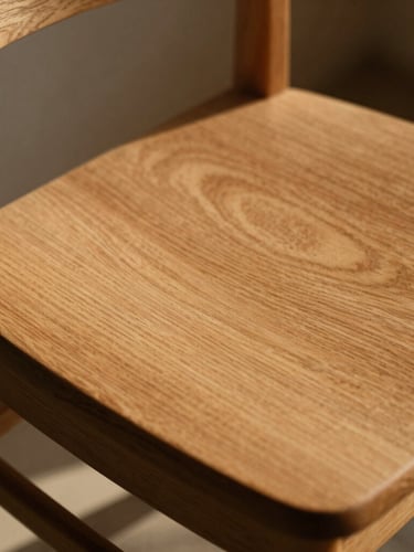 Close-up of a sun-drenched solid oak chair with rich grain textures, warm low-angle afternoon sunlight casting soft long shadows, 35mm photography