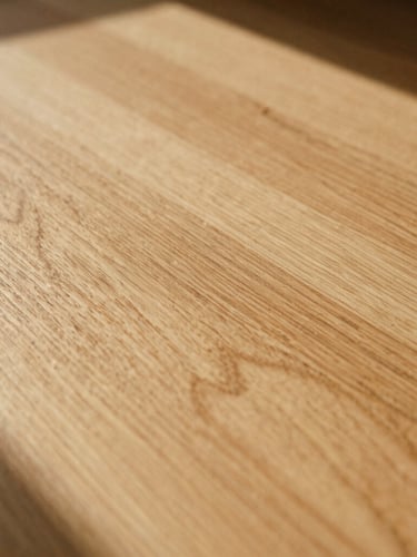 Close-up of natural sun-drenched oak wood grain showing rich texture and soft shadows, warm editorial photography, 35mm