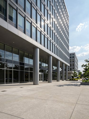 Wide angle daylight shot of a modern multi-tenant commercial office building exterior with a glass facade, clean concrete plaza in the foreground, Washington DC metro area.