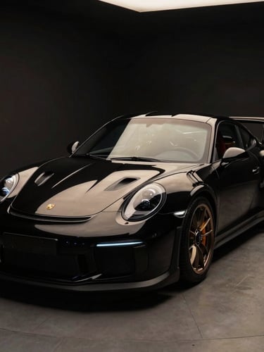 Dramatic 3/4 front angle of a polished black Porsche 911 GT3 RS in a low-key studio, sharp champagne gold reflections on the metallic paintwork, dark background, 50mm