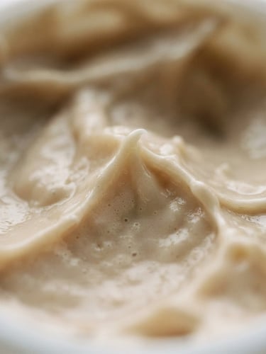 Macro shot of rich cosmetic cream texture, soft natural window light, muted sand and cream tones, shallow depth of field, 35mm