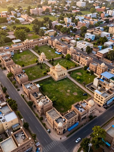 High-resolution drone photography of structured residential land plots in Jaipur at golden hour, showing clean road demarcations and surrounding green landscape, architectural wide-angle lens