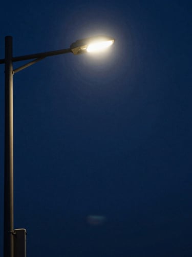 High-contrast chiaroscuro portrait of MoonJX17 under a harsh streetlamp, deep midnight-blue shadows, anamorphic framing.
