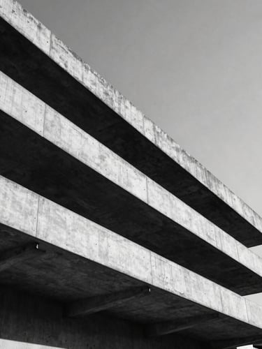 Low-angle heroic wide shot of the brutalist concrete architecture of Accra under hard, direct midday sunlight casting deep, sharp geometric shadows, high-contrast black and white, minimalist composition with generous negative space.