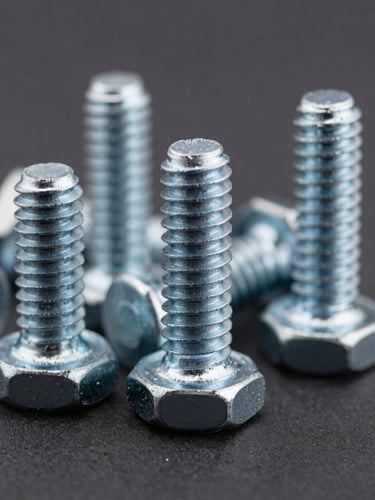 Macro shot of high-tensile steel industrial bolts and threaded screws, sharp metallic textures, dark charcoal background, high-contrast daylight, 50mm