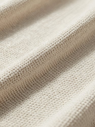 Macro studio photograph of unbleached organic cotton interlock knit fabric, showing technical loop structure, sharp directional shadows, industrial feel.