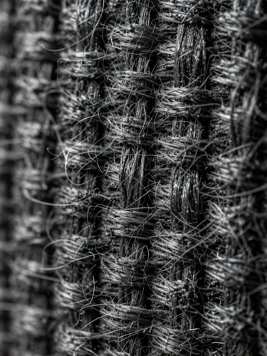 Extreme close-up of a heavy charcoal canvas weave under sharp directional studio lighting, highlighting individual yarn fibers and structural density.