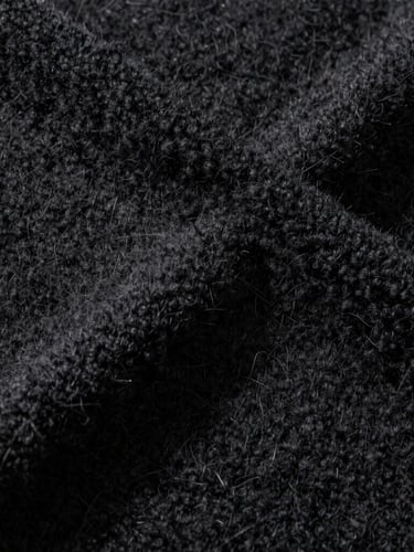 Macro close-up of heavy-weight black loopback cotton fleece texture, high-contrast studio lighting, sharp directional shadows showing fiber depth.