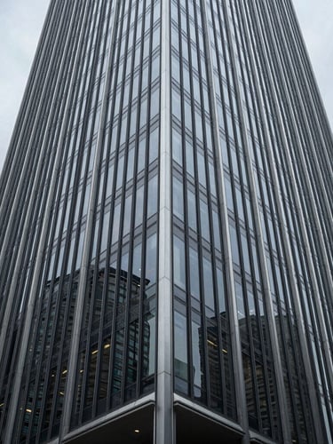 Wide-angle architectural perspective of a modern glass and steel skyscraper facade in Wilmington, cool overcast daylight, sharp geometric reflections, negative space on the left.