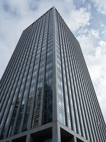 Wide-angle architectural perspective of a modern corporate skyscraper facade in Wilmington, cool overcast daylight, sharp geometric steel and glass lines.