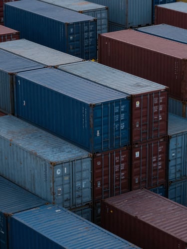 Abstract overhead view of geometric shipping containers stacked in a neat grid, diffused cool twilight lighting.