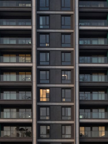 Symmetrical architectural shot of a modern luxury residential tower facade in Gurgaon, soft twilight lighting, deep emerald accents