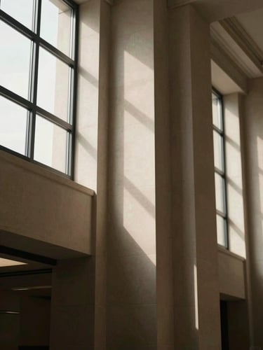 Architectural detail of a classic corporate office with clean lines, soft window light casting elegant shadows on warm stone surfaces, 35mm