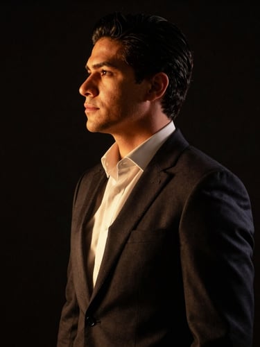 Retrato editorial de perfil de Jayan Cervantes, vistiendo traje oscuro de alta sastrería, iluminación dramática de estudio con sutiles destellos dorados, fondo negro profundo, fotografía de 35mm con enfoque nítido