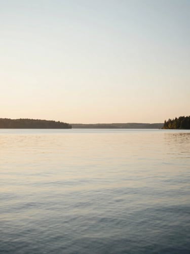 Serene natural landscape of a calm Canadian lake at golden hour, soft horizon, diffused warm light, elegant and quiet atmosphere, 35mm