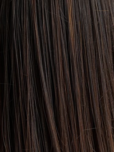 Macro editorial photograph of thick, lustrous raw black hair strands under warm directional studio lighting, showing authentic cuticle texture and natural sheen.