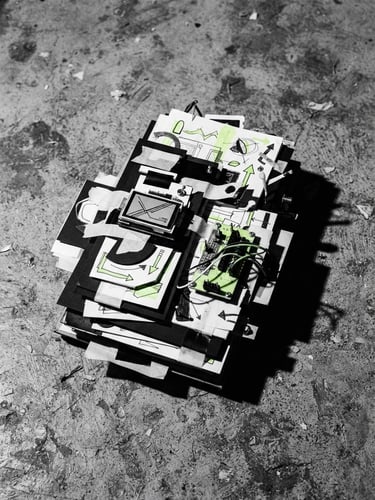 Stark close-up of physical design mockup on a raw concrete floor, harsh direct flash, deep shadows, high-contrast monochrome, 35mm