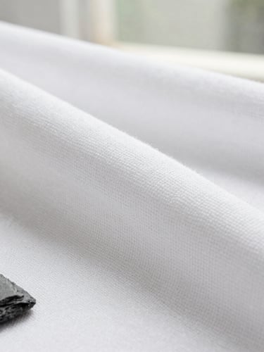 Macro editorial photograph of crisp white cotton fabric weave texture under bright natural daylight, showing high density structure