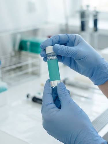 Close-up of clinical laboratory technician hands holding a sterile sample vial with a teal label, bright natural daylight, sterile white and teal palette, sharp focus, 35mm