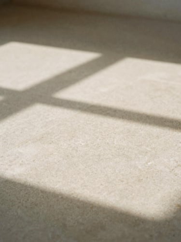 Minimalist close-up of abstract geometric shadows cast on a textured stone surface, soft natural window light, warm neutral tones, high negative space, 35mm