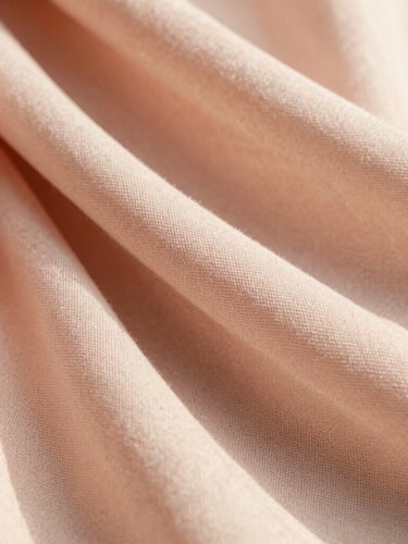 Macro close-up of a soft blush pink georgette scarf showing delicate woven fabric texture, warm diffused golden hour light, soft shadows, premium editorial photography